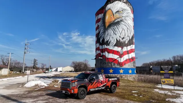 Elite Midnight Roofing work truck parked in front of a painted eagle silo
