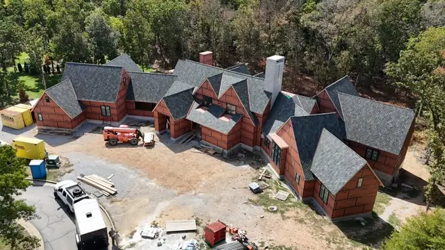Aerial view of a large brick home with a new gray shingle roof going on