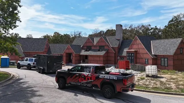 Elite Midnight Roofing truck and trailer at a brick home job site