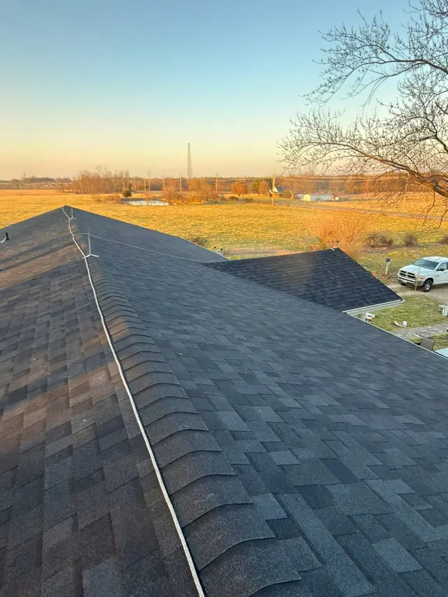 New shingle roof ridge and hip at sunset over farmland