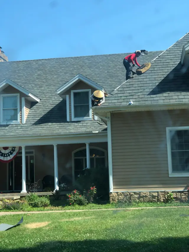 Roofer working on a two-dormer shingle roof on a house