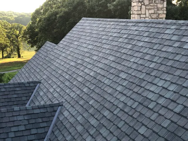 Gray shingle roof with a stone chimney and a step in the roofline