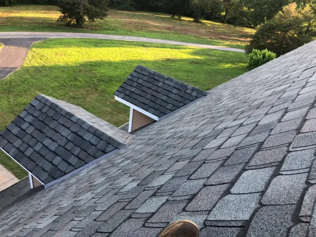Gray shingle roof with a smaller roof section and a lawn below