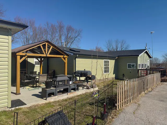 Green-sided home with a wooden gazebo and a new dark shingle roof