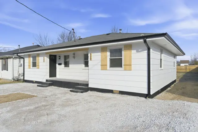 White ranch-style house with a gray roof and black gutters