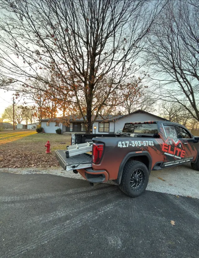Elite Midnight Roofing pickup truck parked in front of a house